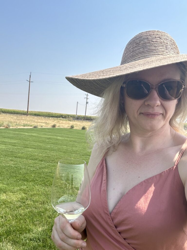 Hayley wearing a wide-brimmed straw hat and sunglasses outdoors on a sunny day